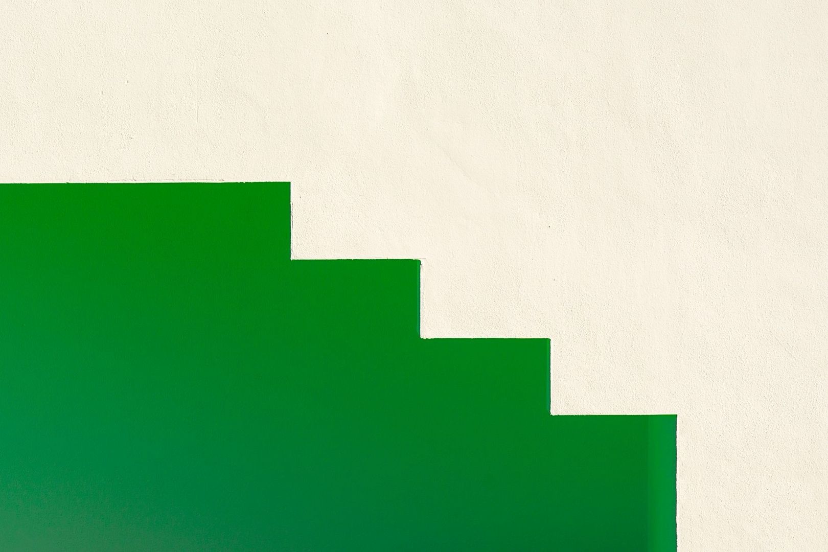 Green stepped geometric shape against a large textured off-white field
