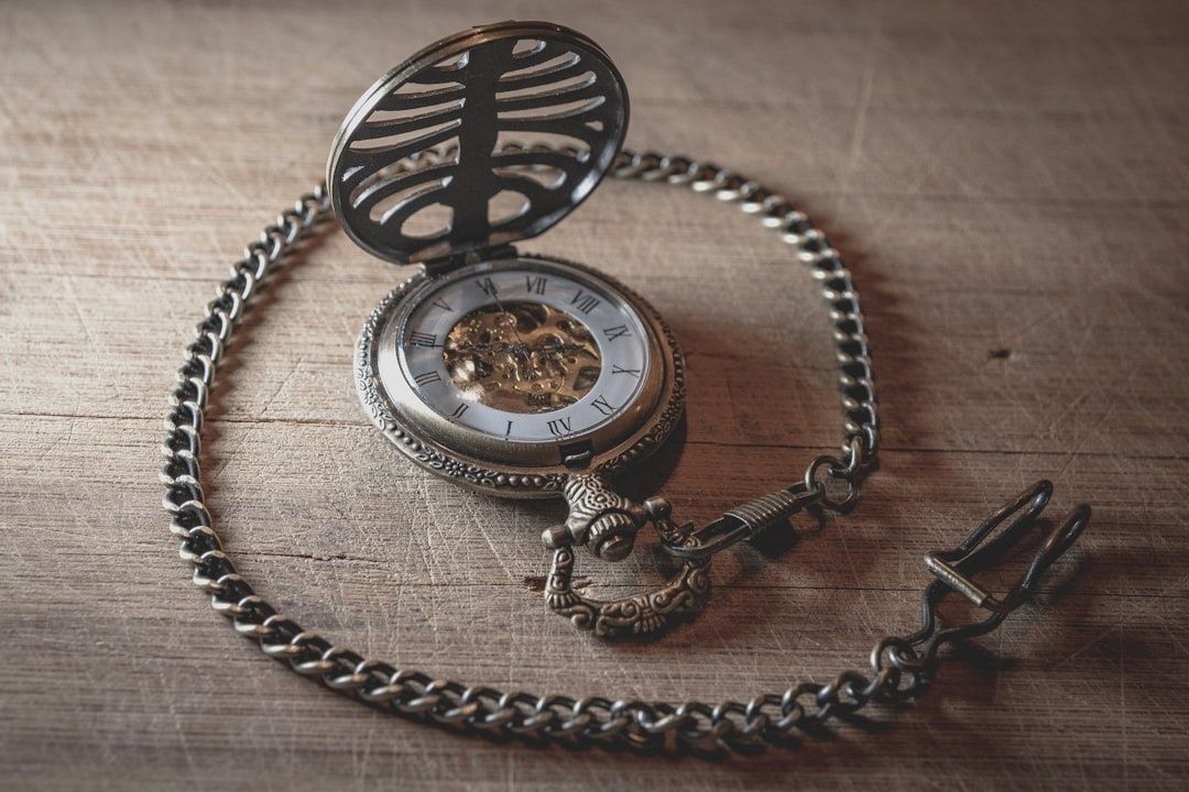 Open antique pocket watch and chain on a worn wooden table