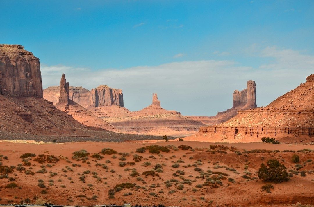 Red-rock desert valley with towering sandstone formations under blue sky